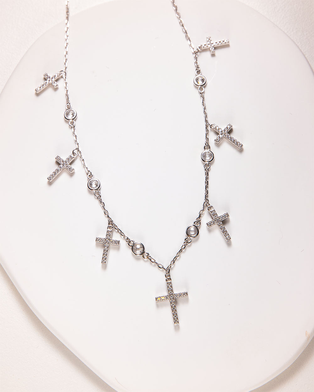 Sterling silver necklace featuring seven sparkling Cubic Zirconia crosses, with a bold centerpiece cross and dainty surrounding ones.